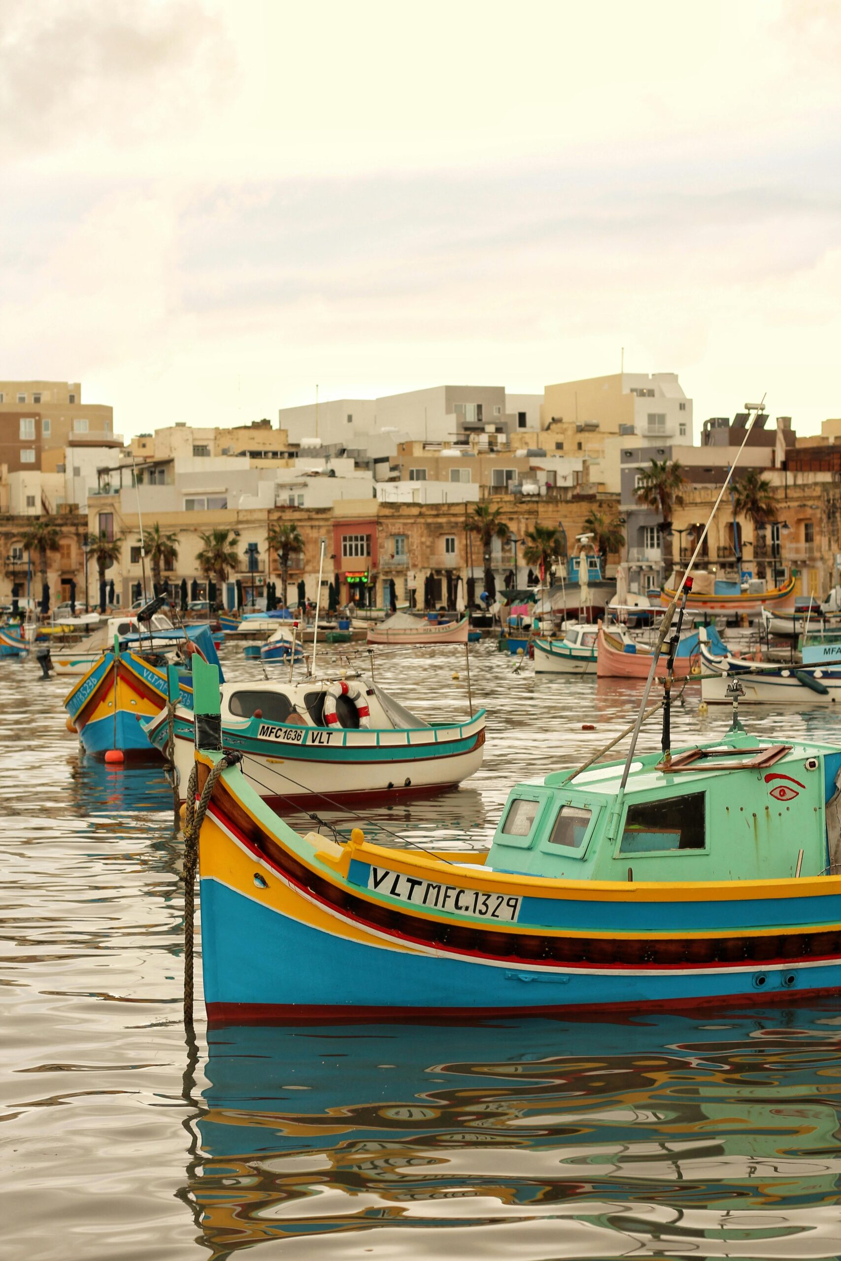 Vibrant fishing boats float on Marsaxlokk, Malta's serene waterfront, capturing the essence of Mediterranean charm.